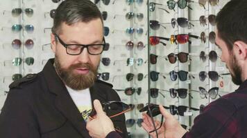 professionnel optométriste montrant des lunettes pour vente à le sien Masculin client video