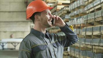 Happy factory worker in a hardhat smiling talking on the phone video