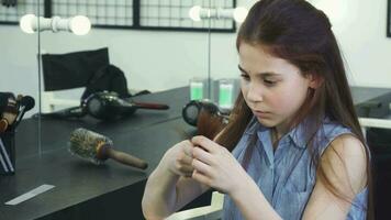 Little cute girl looking sad examining her damaged hair with split ends video