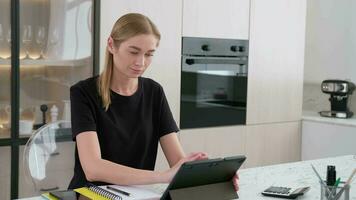 Business woman working at home sitting at the table using a tablet. video