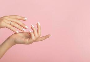 Hands of a beautiful well-groomed woman with feminine nails on a pink background. Manicure photo