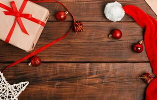 Navidad tarjeta. rojo Navidad pelotas son dispersado en un oscuro marrón de madera fondo, arte regalo caja foto