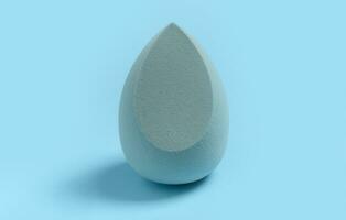 Blue cosmetic makeup sponge on a minimal background. Egg shape. Tool for applying foundation cream photo