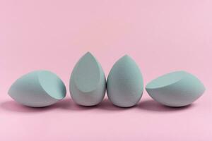 Blue cosmetic makeup set sponge on a minimal pink background. Tool for applying foundation cream photo