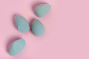 Blue cosmetic makeup set sponge on a minimal pink background. Tool for applying foundation cream photo