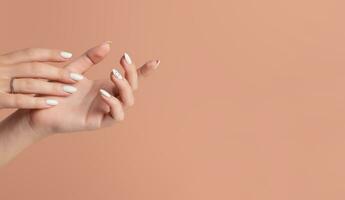 Hands of a beautiful well-groomed woman with feminine nails on a beige background. Manicure photo