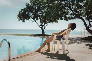 mujer teniendo broncearse por nadando piscina al aire libre a verano tiempo. foto