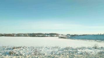 Aussicht von das Fenster von ziehen um Auto auf schneebedeckt Felder auf sonnig Tag video