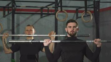Male crossfit athletes warming up at the gym lifting barbells video