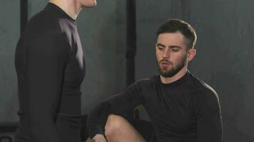 Handsome bearded male personal trainer helping young man at the gym video