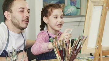 Proud father watching his lovely daughter painting a picture video