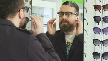 Mature man trying on new glasses in front if the mirror at the store video