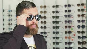 maduro hombre molesto en Gafas de sol a el ópticos Tienda video