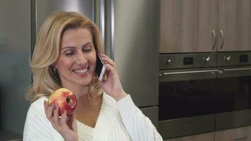 dichtbij omhoog van een prachtig vrolijk vrouw pratend Aan de telefoon Holding een appel video