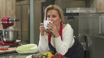 atraente maduro mulher tendo café às a cozinha às casa video