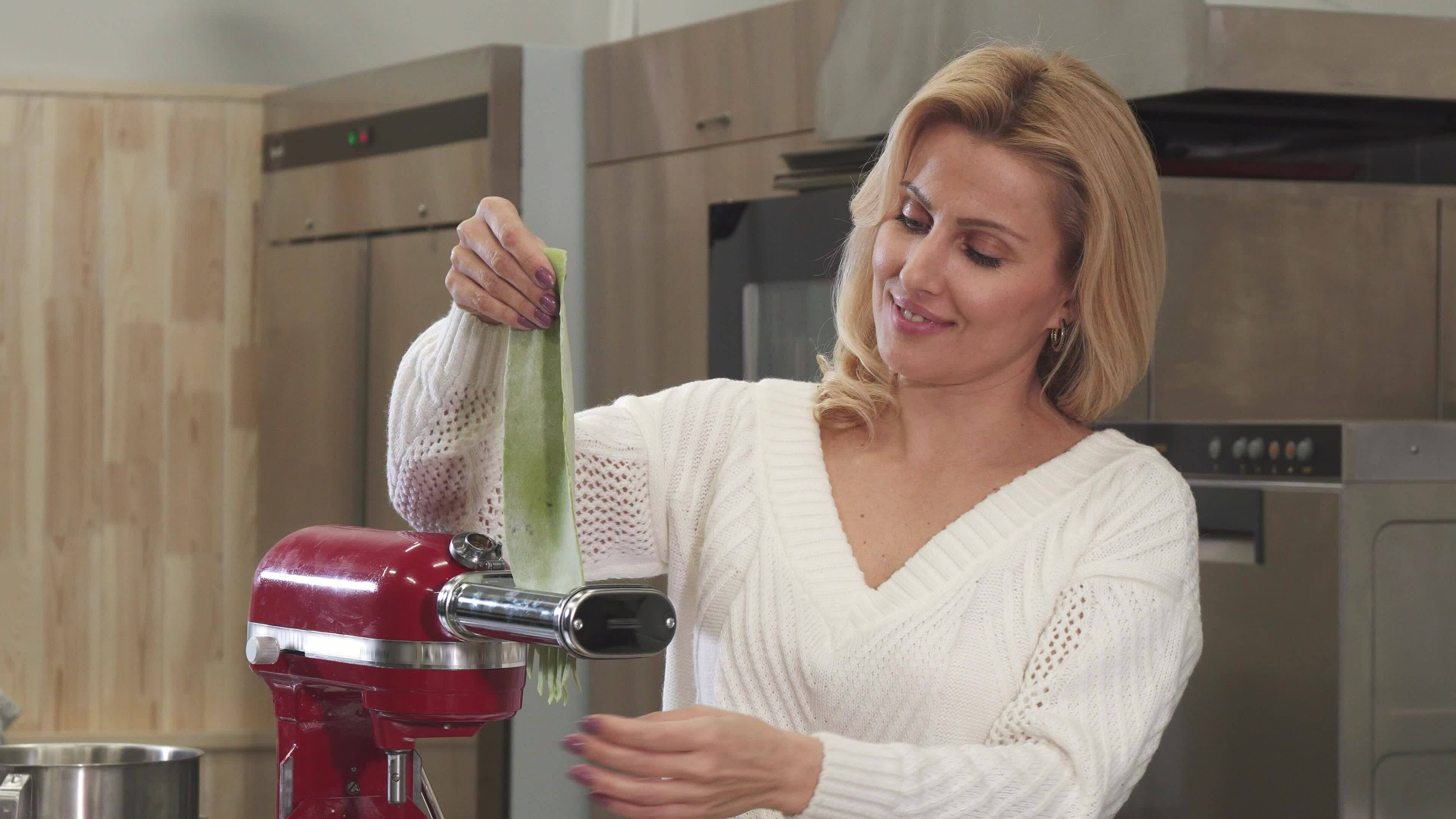 Beautiful mature housewife using pasta machine making homemade pasta