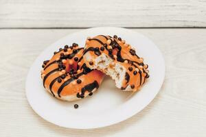 Donuts with icing on a plate on a wooden background photo
