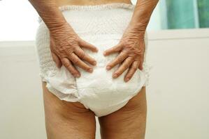 Asian senior woman patient wearing adult incontinence diaper pad in hospital. photo