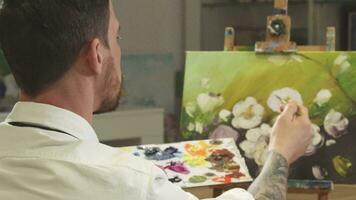 arrière vue coup de une Masculin artiste travail sur une La peinture à le sien art studio video