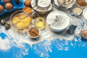 Baking ingredients on blue color background, top view photo