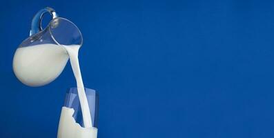 Pouring milk with splash on blue background photo