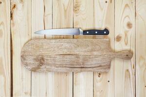 Chopping board with knife on wooden table top view photo