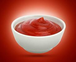 Ketchup in white bowl isolated on red background. photo