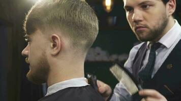 Close up of a handsome professioanl barber stylign hair of a man video