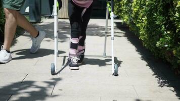 child with walking frame and knee orthosis outdoor video