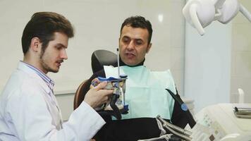 Professional dentist showing dental mold to his mature patient video