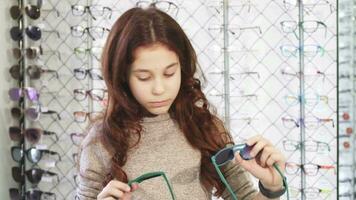 jolie peu fille à la recherche confus choisir entre deux paires de des lunettes de soleil video