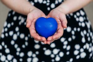 azul corazón en el manos de un mujer en un polca punto vestir foto