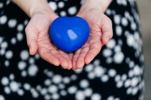 Blue heart in the hands of a woman in a polka dot dress photo