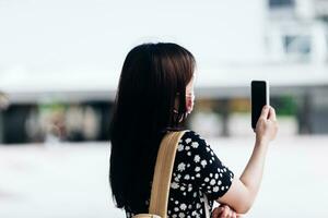 Young woman wearing face mask and using mobile phone in the city. photo