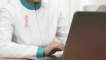 Close up of a pink ribbon cancer awareness female doctor working at the clinic video