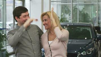 feliz casal rindo Alto cinco depois de comprando uma Novo carro às a concessionária video