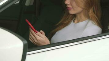 Cropped shot of smiling woman sitting in a car texting on her smart phone video