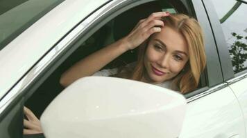 Stunning red haired woman looking at the side mirror sitting in her car video