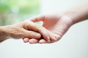 Asian young boy holding old grandmother woman hand together with love and care. photo