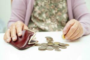 Retired elderly woman counting coins money and worry about monthly expenses and treatment fee payment. photo