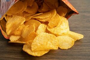 Potato chips, delicious BBQ seasoning spicy for crips, thin slice deep fried snack fast food in open bag. photo