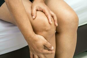 mujer asiática mujer paciente toca y siente dolor en la rodilla, concepto médico saludable. foto