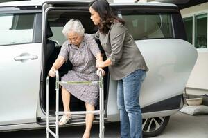 asiático mayor mujer paciente caminar con caminante preparar obtener a su auto, sano fuerte médico concepto. foto