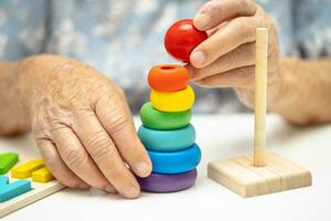 Alzheimer disease AD, Asian elderly woman patient suffering from dementia learn practical motor skills rehabilitation. photo