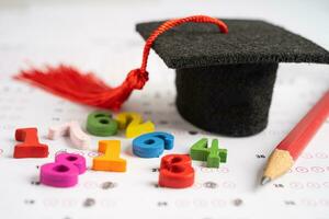 Graduation gap hat and pencil on answer sheet paper, Education study testing learning teach concept. photo