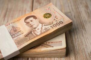 Stack of Thai baht banknotes on wooden background, business saving finance investment concept. photo