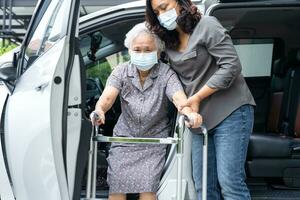 asiático mayor mujer paciente sentado en caminante preparar obtener a su auto, sano fuerte médico concepto. foto