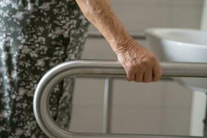 Asian elderly woman patient use toilet bathroom handle security in nursing hospital, healthy strong medical. photo