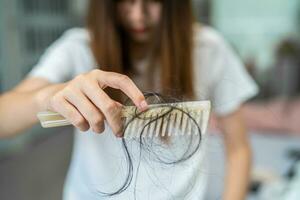 Asian woman have problem with long hair loss attach to comb brush. photo