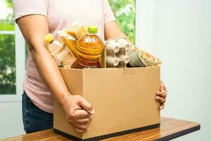 voluntarios poniendo varios alimentos secos en cajas de donación para ayudar a las personas. foto